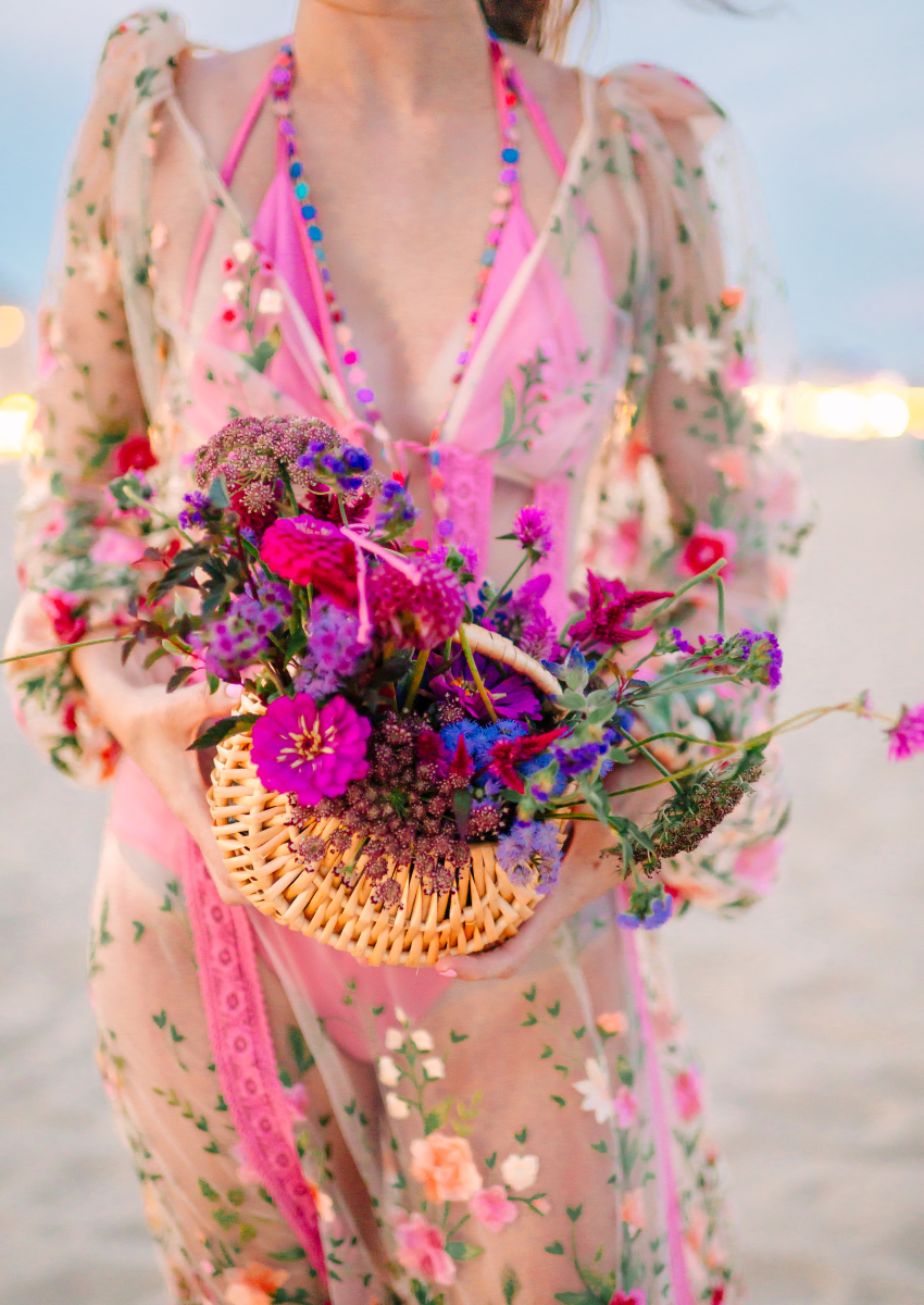 Florals and Film Styled Shoot of a girl wearing a bathing suit coverup carrying a wicker purse filled with wildflowers