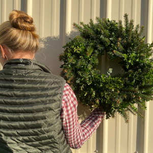 Woman holding a wreath of mixed Christmas greens
