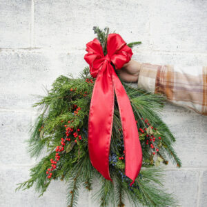 Christmas Swag held in front of a grey cement wall.