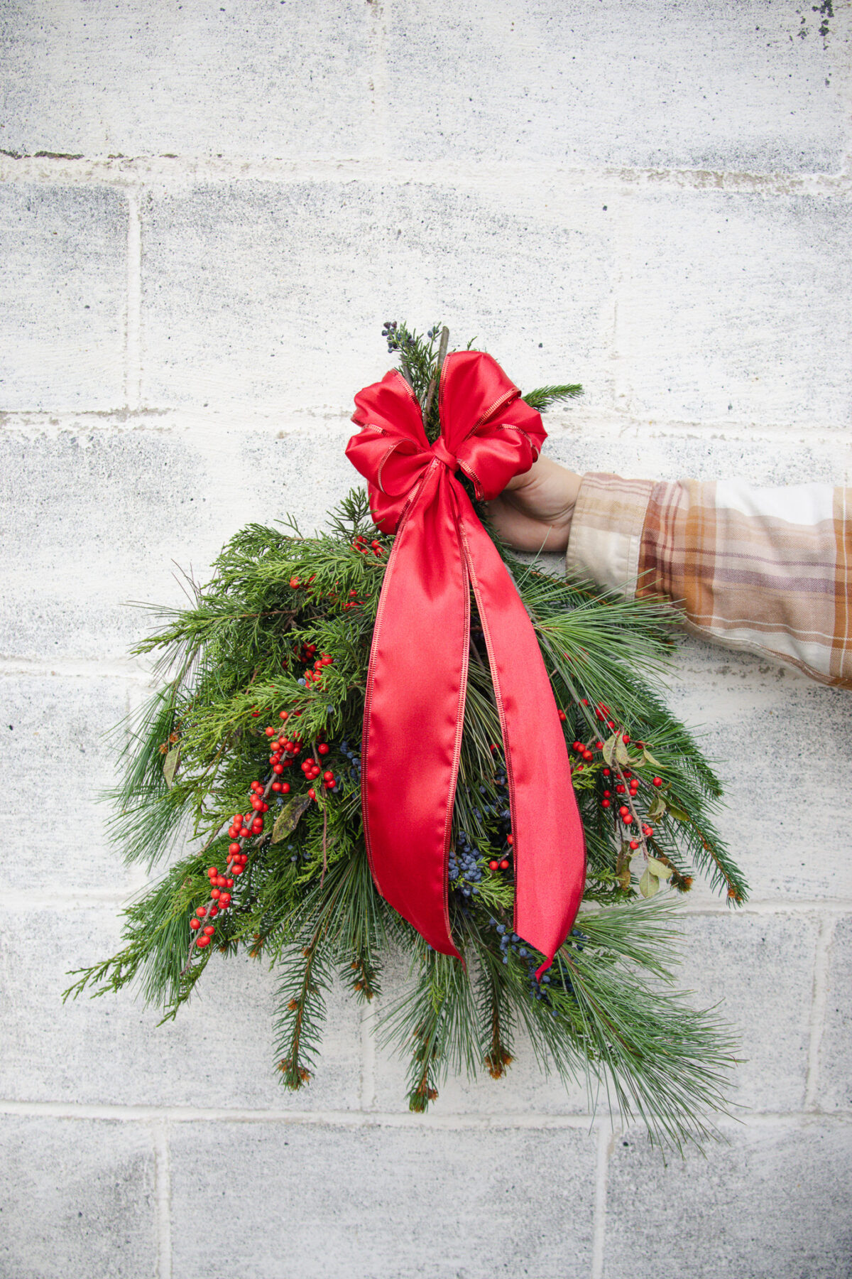 Christmas Swag held in front of a grey cement wall.