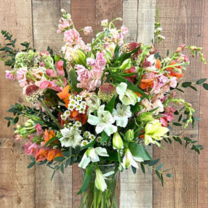 Flower arrangement in a vase using local flowers in white, pink, and orange.