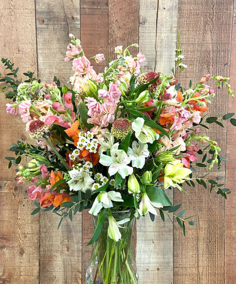 Flower arrangement in a vase using local flowers in white, pink, and orange.