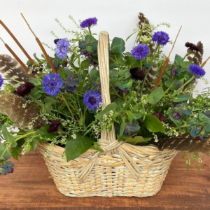 Sympathy Basket Arrangement with blue flowers and feathers.