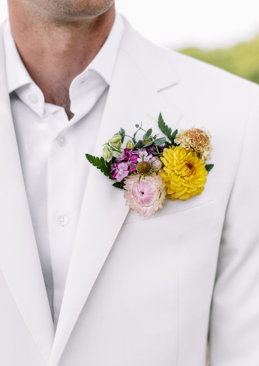 Colorful flowers in a pocket square style boutonniere in a pale khaki suit jacket.