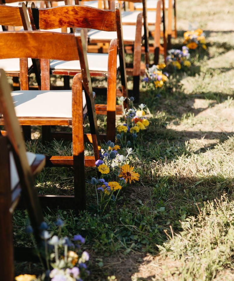 wedding isle with flowers in the ground with wooden chairs