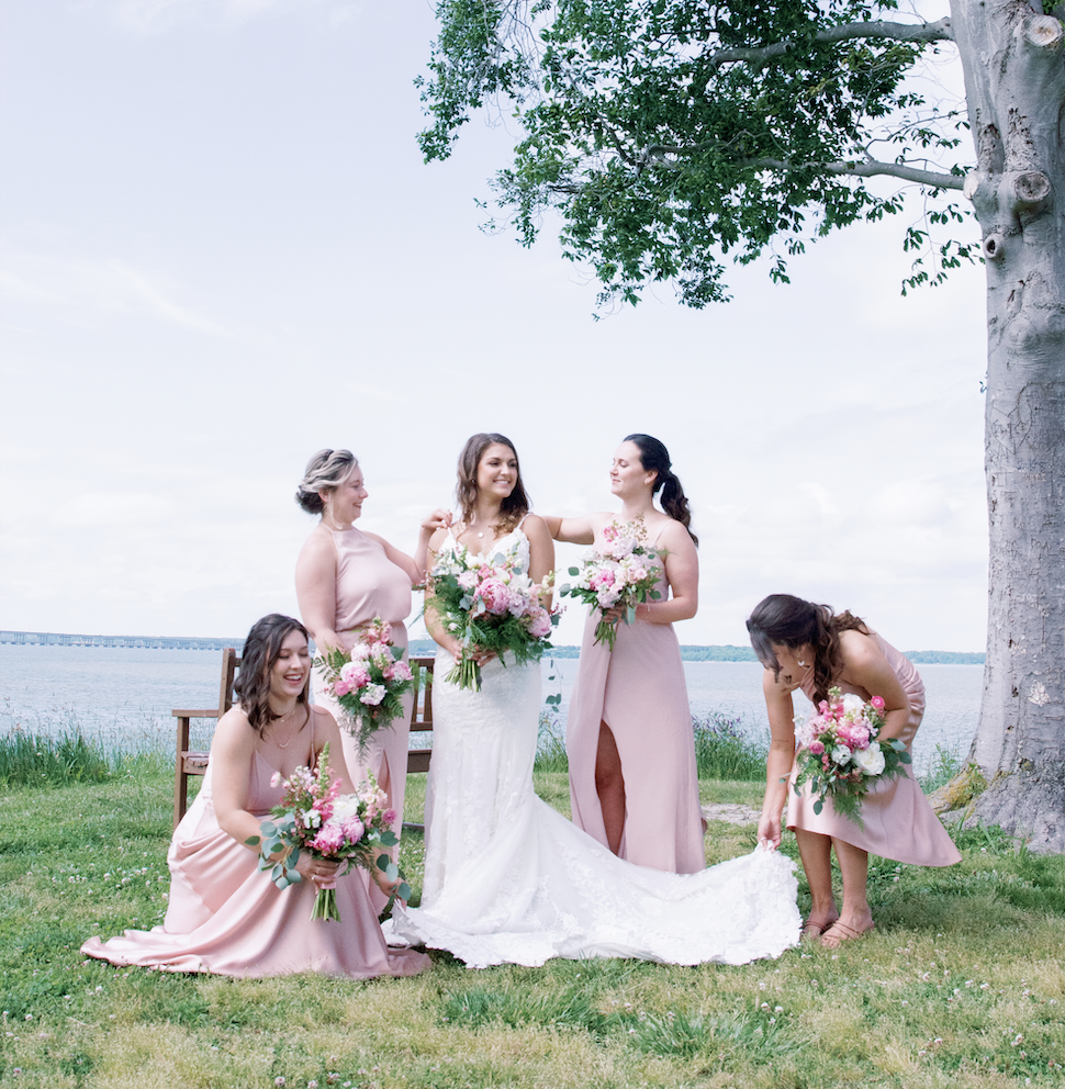 Bride and bridesmaid in front of water with flowers