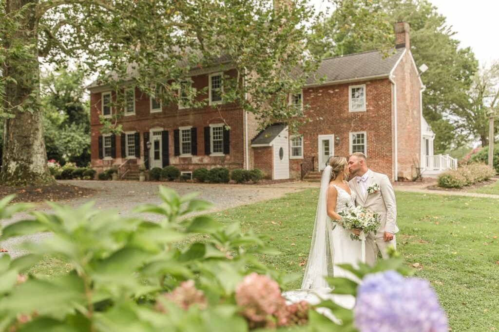 bride and groom in front of the venue house at worsaell manor