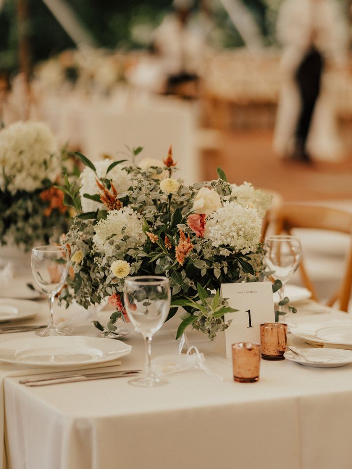 reception tables with compotes filled with pastel white flowers and rose gold votives