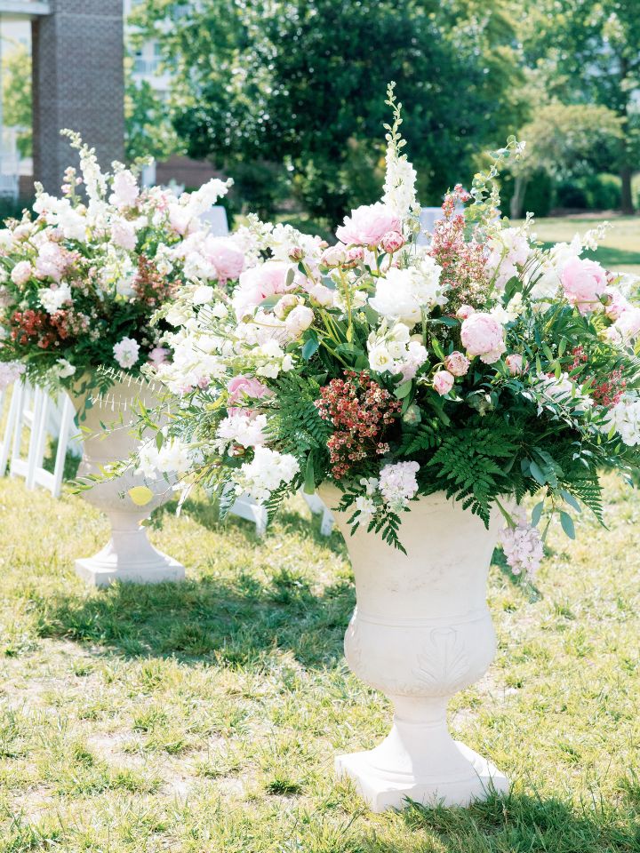 pedestal urns at the back of the aisle with pink and white flowers