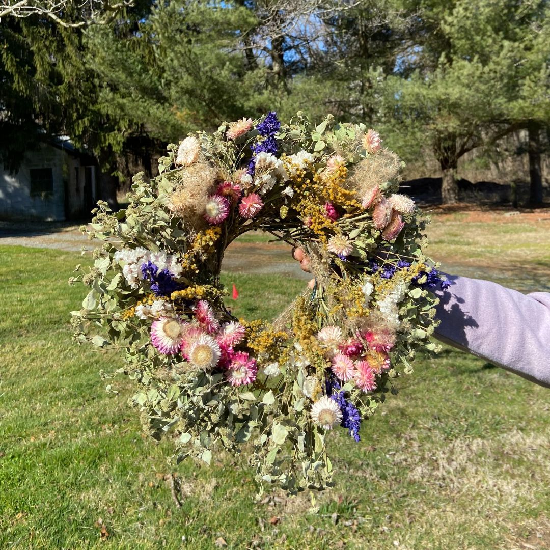 Spring Dried Floral Wreath held up outside on a sunny day.
