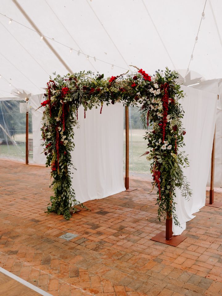Chuppah under a tent with full florals on the front frame.