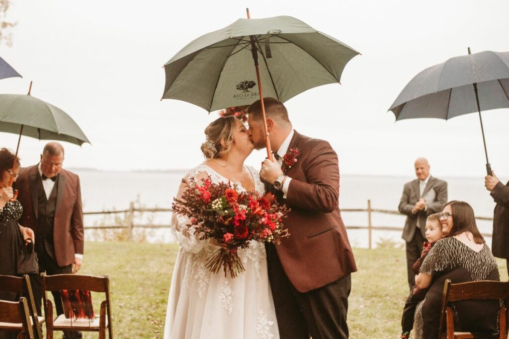 Bride and Groom kiss under a black umbrella at a Halloween Wedding