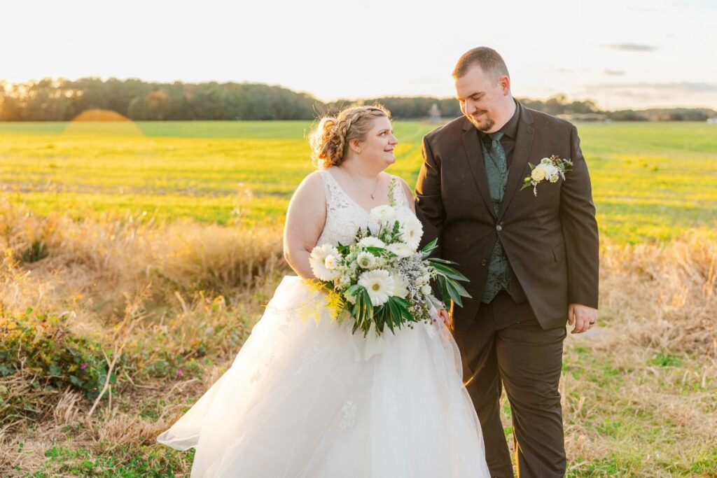 Bride and Groom walk in a winter field with their green and white wedding flowers.