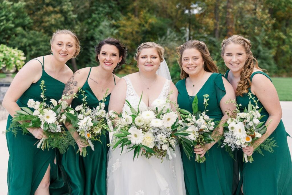Bride and bridesmaids wearing emerald green hold their green and white wedding flowers.