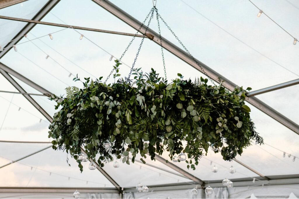 Greenery Chandelier hangs from ceiling of clear top tent.