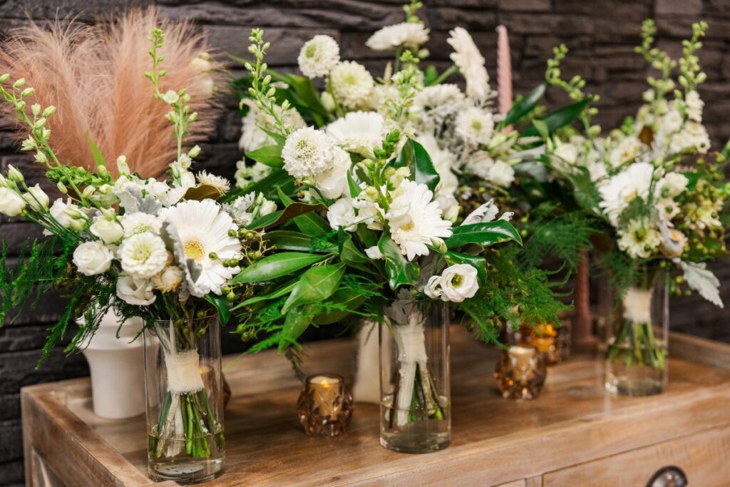 Bridal and bridesmaid bouquets in white and green wedding flowers lined up in vases.