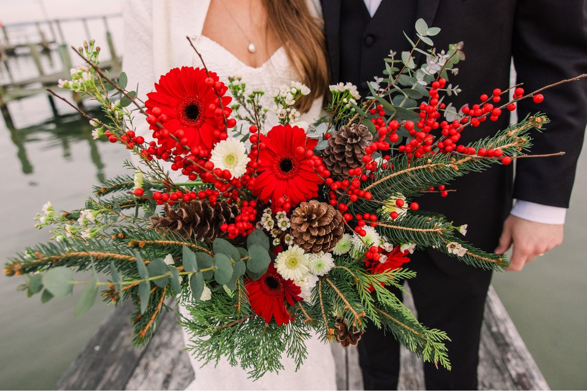 Close up of bridal bouquet in red, white, and evergreens.