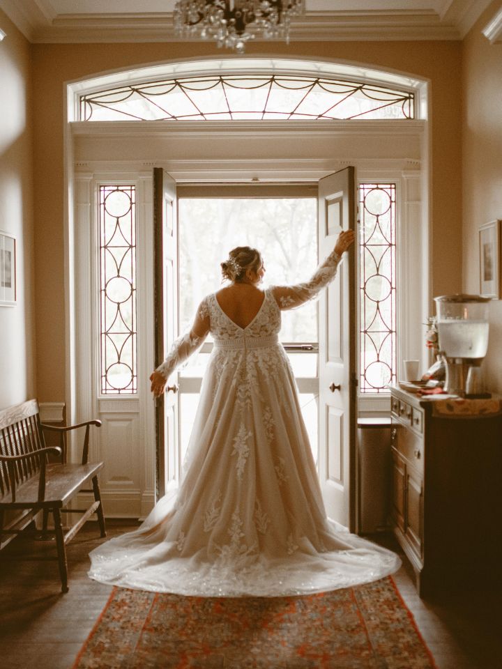 Bride looks out of an old manor house window.