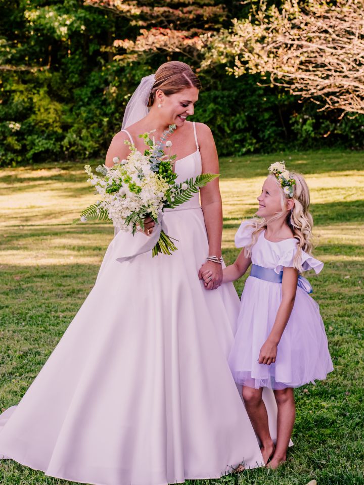 Bride smiles at flower girl, who is wearing a flower crown.