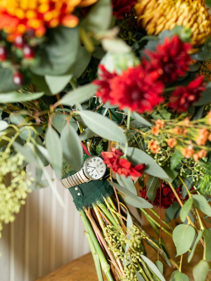 Close up of watch wrapped around bridal bouquet stems.