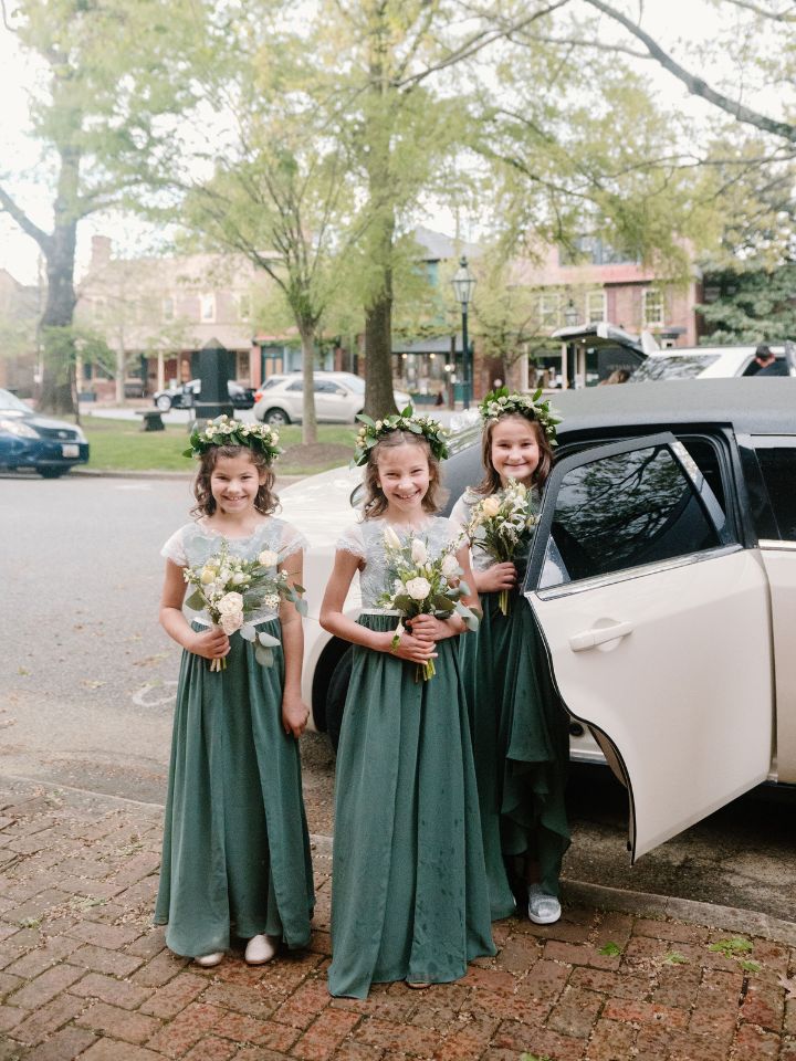 Junior Bridesmaids stand on a brick sidewalk outside the church with their flower crowns and bouquets.
