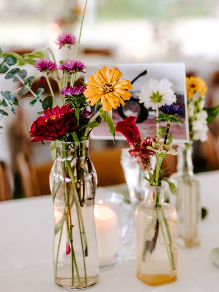 Bud vases filled with colorful summer DIY wedding flowers.