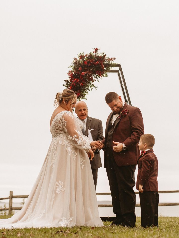 Bride and Groom stand at halloween theme wedding ceremony with officiant and son.