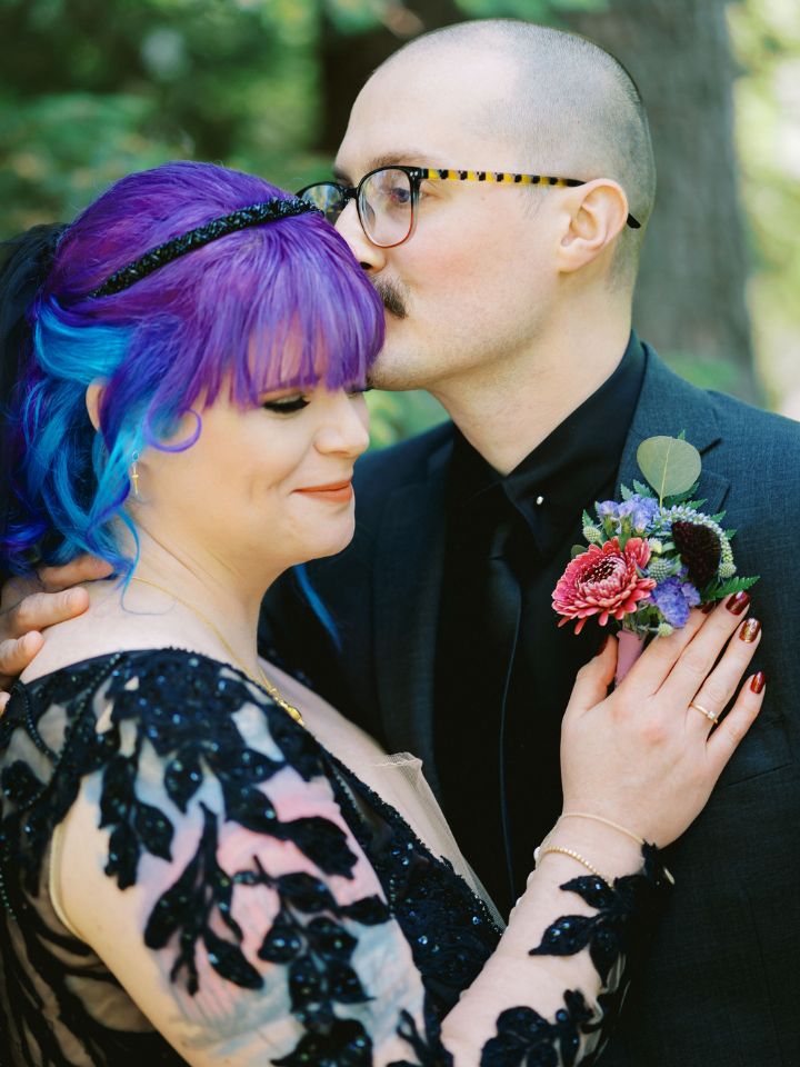 Bride and Groom wearing black with moody jewel tone flowers.