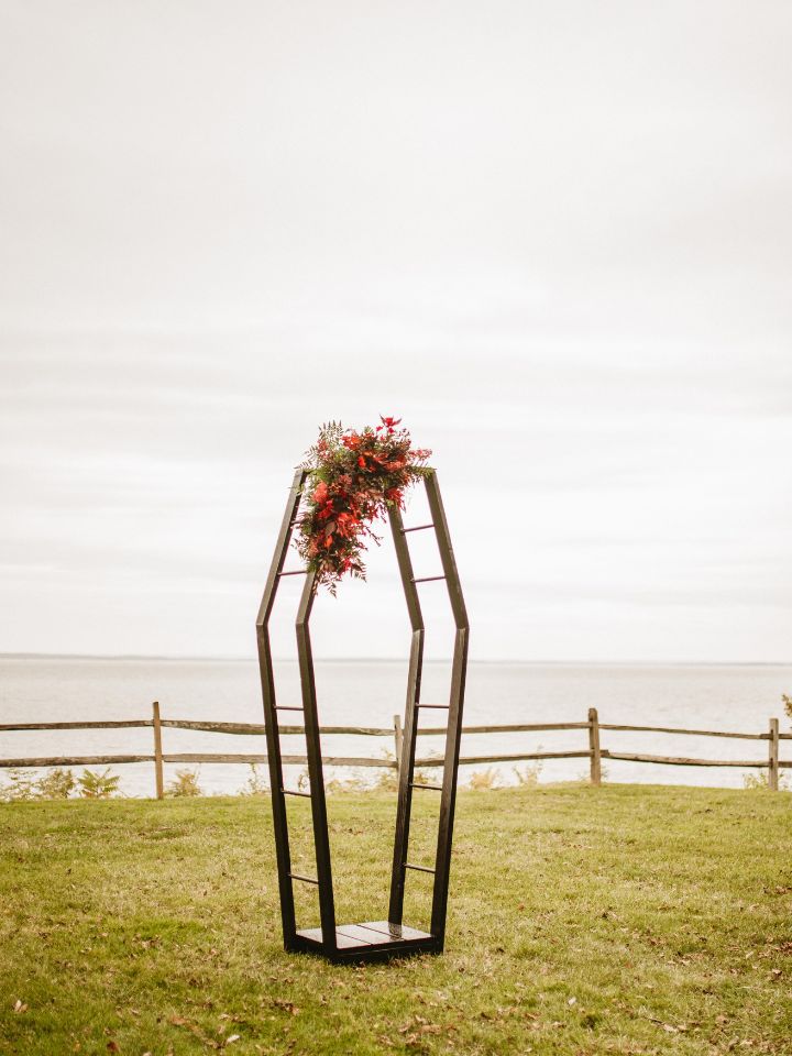 Coffin shape wedding arch with moody jewel tone florals.