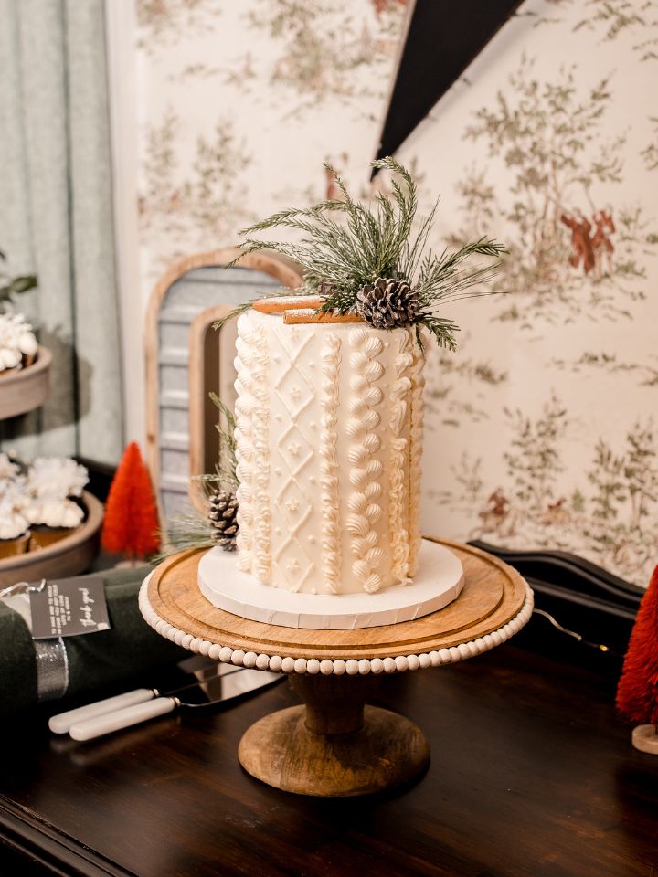 An ivory single tier wedding cake sits on a gold platter, and has cable knot sweater texture in the icing.