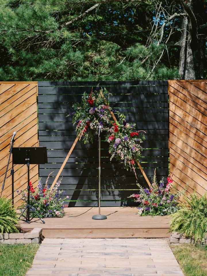 Triangle wedding arch with jewel tone flowers.