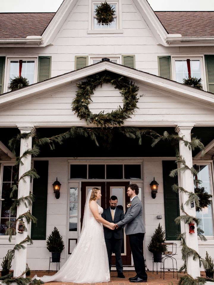 Front porch of old farmhouse with Christmas greenery for a wedding ceremony.
