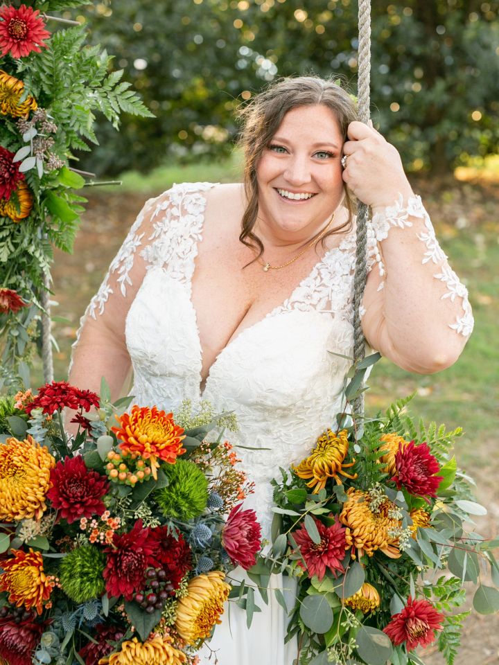 Bride smiles from her floral covered swing.