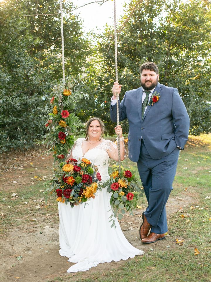 Bride and Groom pose at a floral covered swing.