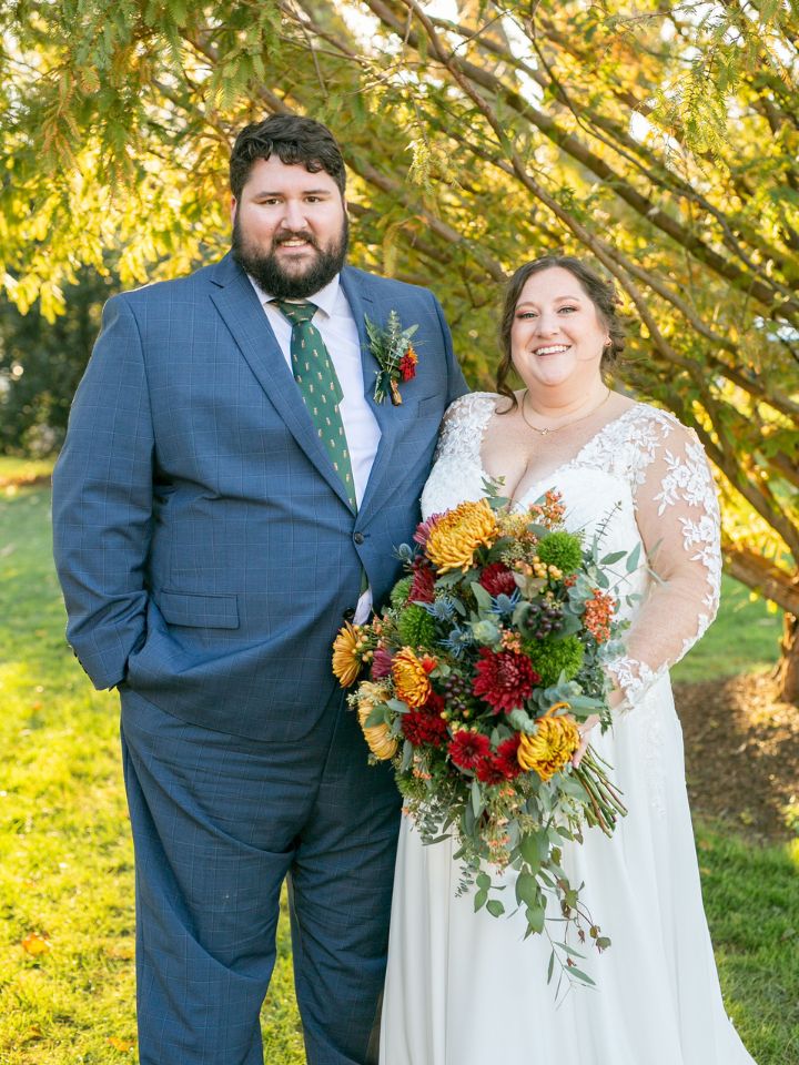 Bride and Groom smile at camera holding fall flowers.