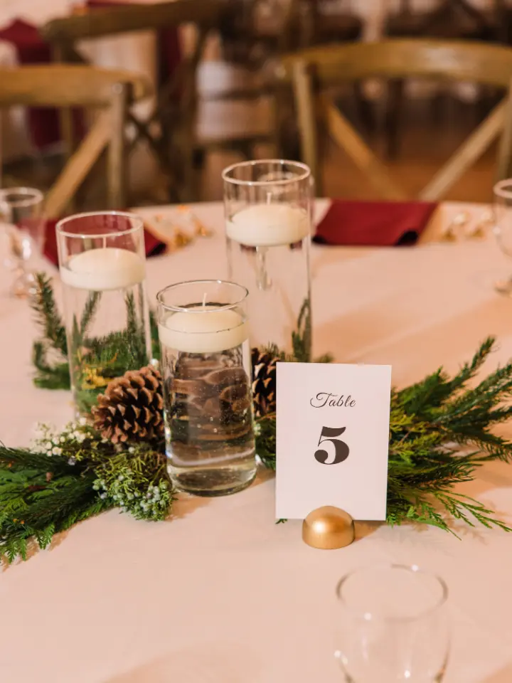 Pine cones and greenery with floating candles as a centerpiece on a round table