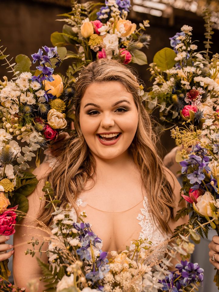 Bride smiles in a frame of her bridesmaid bouquets