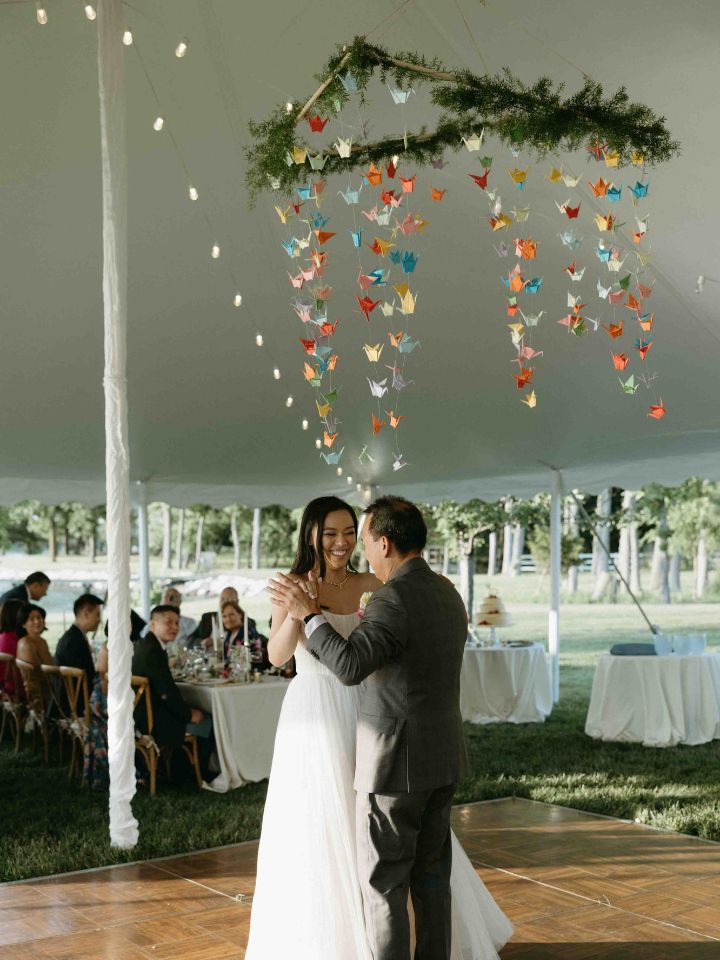 Father and daughter share a dance at wedding under a colorful tent installation