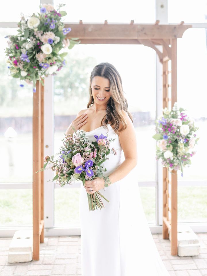 Bride smiles down at her floral bouquet.