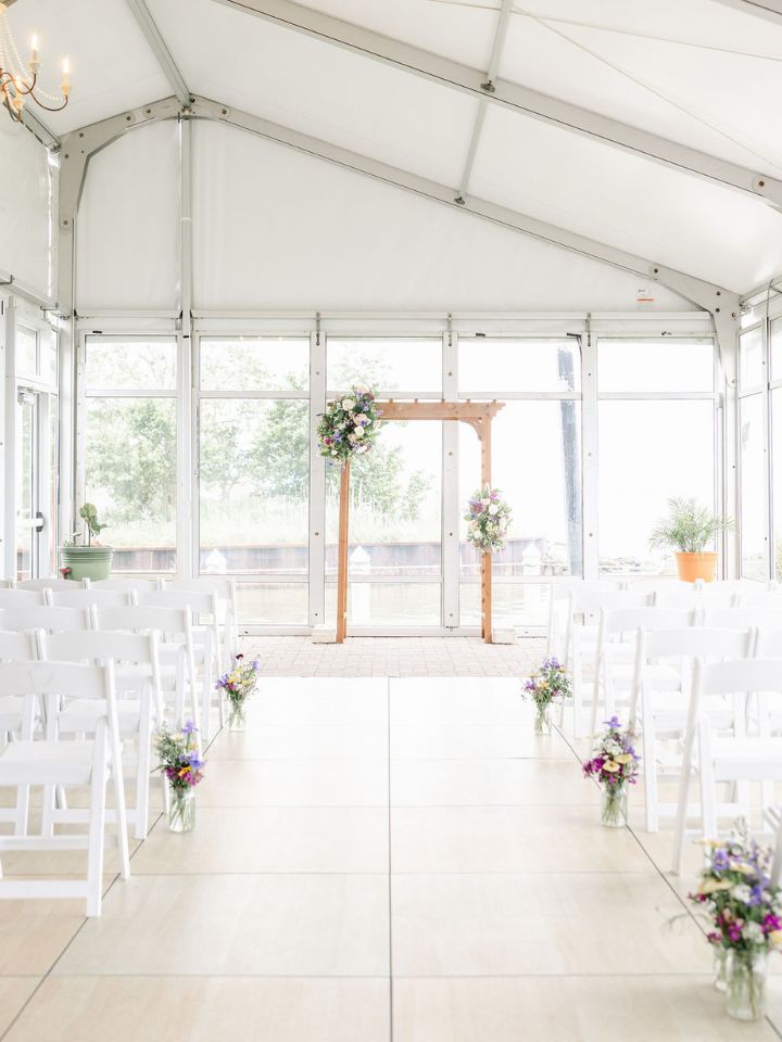 Wedding ceremony with floral aisle and wooden arch.