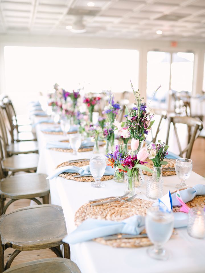 A long table with white linen, and bud vases down the center.