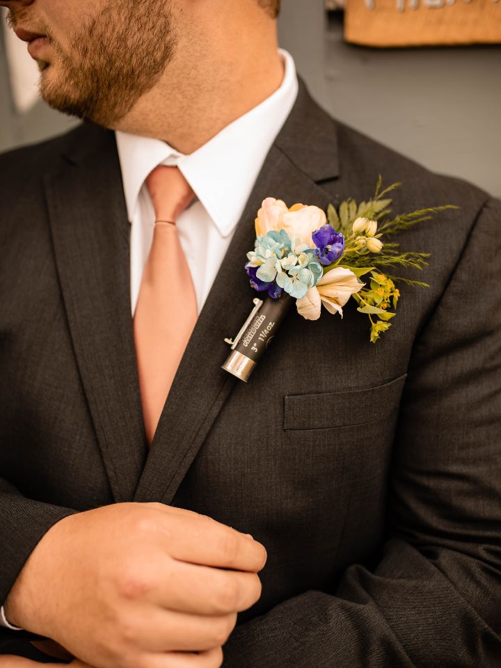Close up of black suit with floral boutonniere in a shotgun shell.