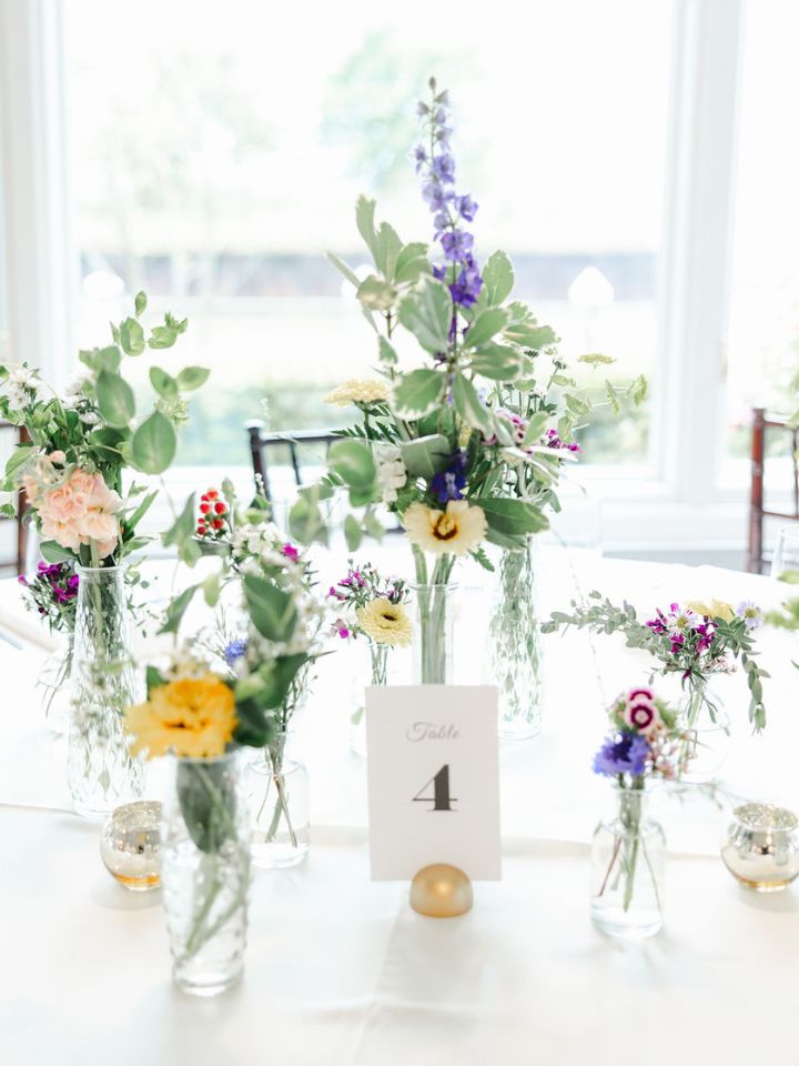 Bud vases with spring flowers at a May wedding.