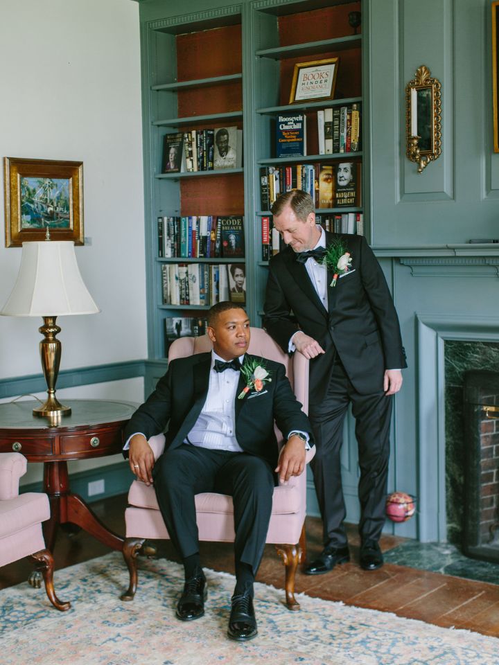 Two grooms pose in an old manor house library.