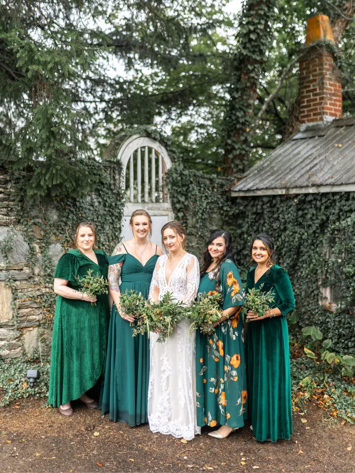 Bride with her bridesmaids all in emerald green dresses, slightly different