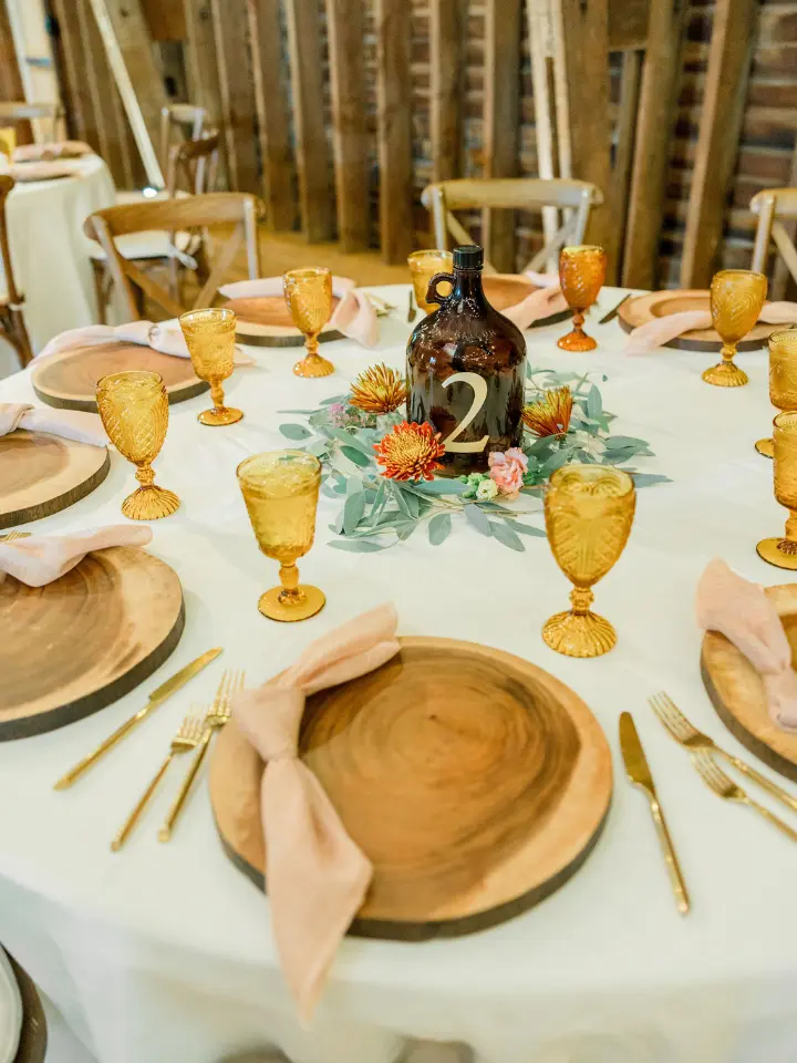Table setting with yellow goblets gold chargers and pink napkins tied together