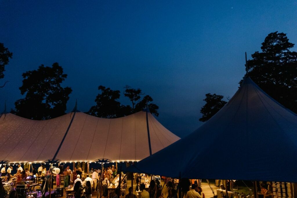 Sailcloth tent at night lit by strand lighting.