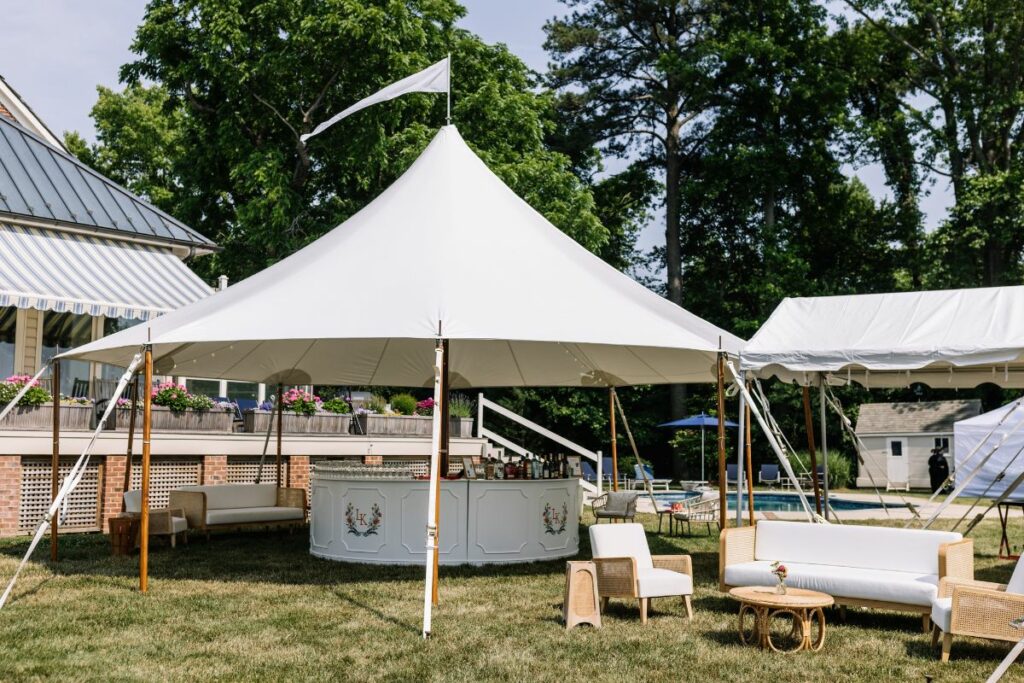 A round sailcloth tent covers a circular bar, next to an outdoor lounge area.