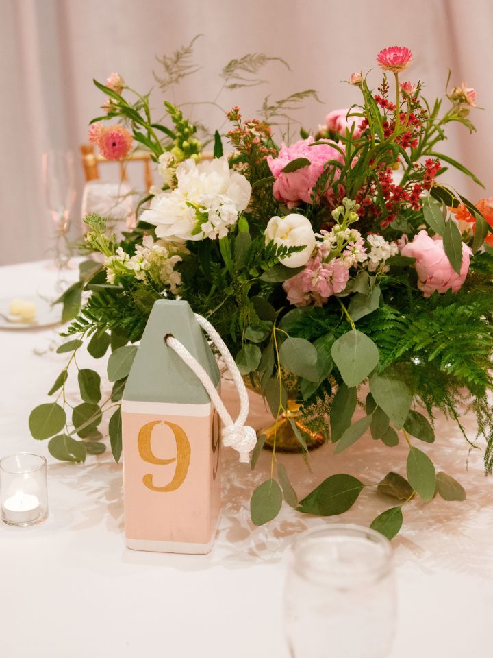 Wedding table is set with a buoy table number and pink floral arrangement.