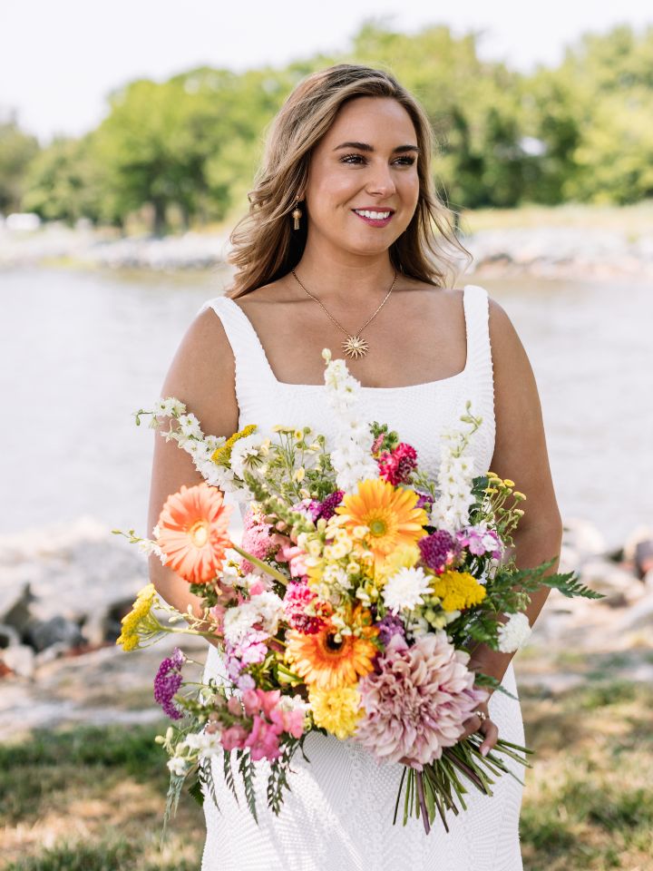 Bride smiles holding a bright citrus wedding color bouquet